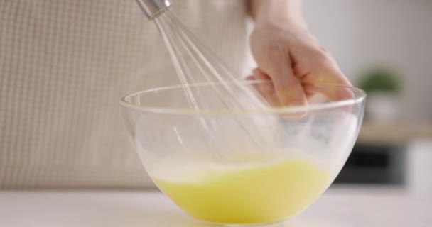 Jovem mulher mexendo ovos com misturador de mão, close-up. Cozinhar na cozinha da casa. Movimento lento — Vídeo de Stock