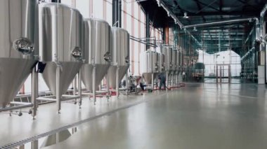 Modern bira fabrikasında parlak metal bira tankları. Geniş açı panoramik görüntü, kamera hareket ediyor