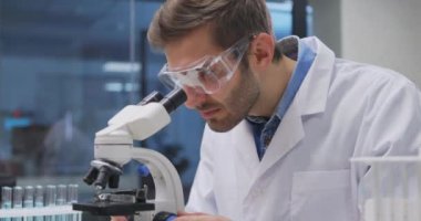 Laboratuvarda çalışan bir bilim adamı. Doktor mikroskop kullanarak tıbbi araştırma yapıyor. Laboratuvar aletleri: mikroskop, test tüpleri, ekipmanlar. Biyoteknoloji, kimya, bilim, deneyler ve sağlık konsepti.