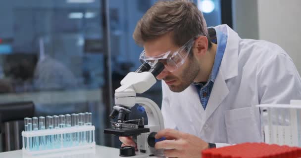 Científico trabajando en el laboratorio. Doctor haciendo investigación médica usando microscopio. Herramientas de laboratorio: microscopio, tubos de ensayo, equipo. Biotecnología, química, ciencia, experimentos y concepto de salud. — Vídeo de stock