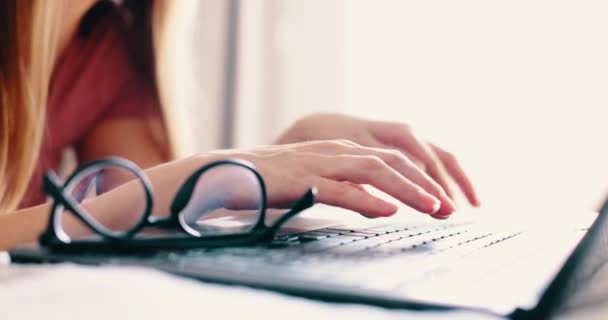 Kvindelige hænder skrive på laptop tastatur på sengen i soveværelset, tæt på visning. Tager briller fra tastaturet – Stock-video