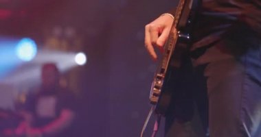Adam sahnede gitar çalıyor. Genç adam elektro bas gitar çalıyor. Sanatçı gitarist eli yakın çekim
