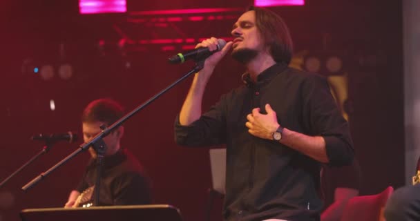 Vista laterale ritratto di un uomo che canta al microfono su sfondo chiaro. Elegante ragazzo figo esibirsi in concerto sul palco. Al rallentatore. Concetto di musica e concerto. — Video Stock