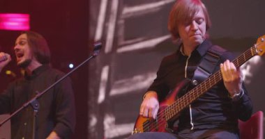 Rock Konseri 'nde bas gitarist sahnede gitar çalar. Arka planda şarkıcı. Yavaş Hareket
