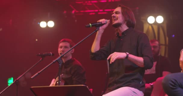 Uomini che cantano al microfono su sfondo chiaro. Elegante ragazzo figo esibirsi in concerto sul palco. Al rallentatore. Concetto di musica e concerto. — Video Stock