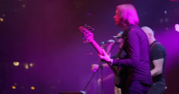 Задний вид бас-гитариста на сцене, играющего на гитаре на концерте. Медленное движение — стоковое видео