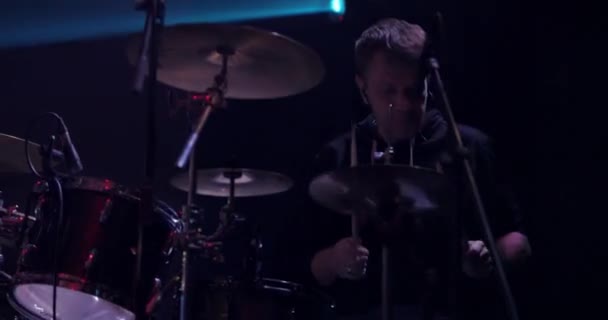 Muzikant drummer spelen tegen een achtergrond van felle lichten. Live concert van popband op het podium. Langzame beweging — Stockvideo