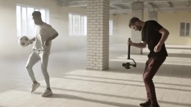 Sahne arkasında. Seçim sistemli genç adam siyahi futbolcuyu eğitirken video çekiyor.