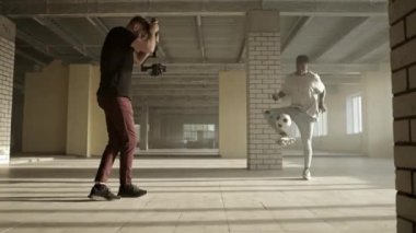 Sahne arkasında. Seçim sistemli genç adam siyahi futbolcuyu eğitirken video çekiyor.
