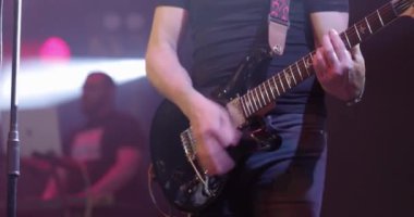 Adam elektro gitar çalıyor. Gitaristler sahnede performans sergiliyor. Canlı konser. Yakın çekim, yavaş çekim