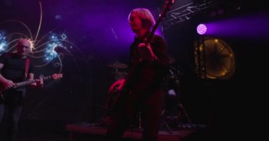 Canlı konser. Bir pop grubunun performansı, sahnede müzik grubu. Sahne ışığı ve parlak ışıklar. Vokalist, gitarist. Yavaş çekim