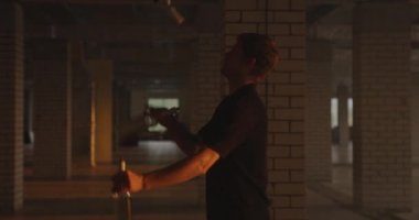 Profesyonel barmenin silueti şişeleri idare eder. Barmen, park yerindeki parlak güneş ışığında salonda pratik yapıyor. Yavaş çekim