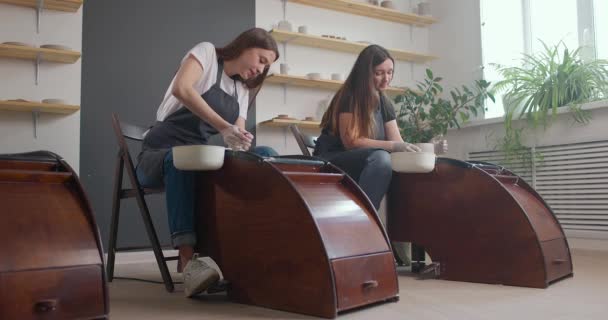 Concept de studio de poterie. Deux jeunes femmes utilisant la roue de poterie, céramique artisanale, créatif. Mouvement lent — Video