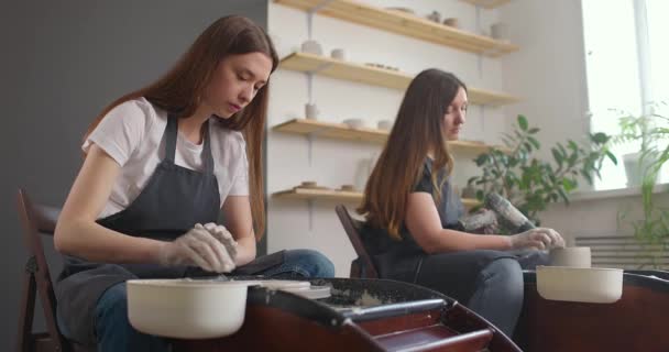 Concepto de estudio de cerámica. Dos mujeres jóvenes usando rueda de cerámica, cerámica hecha a mano, creativa. Movimiento lento — Vídeo de stock