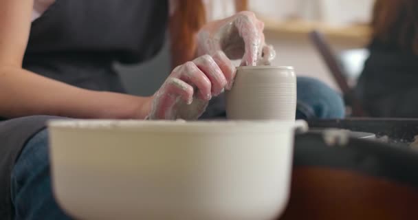 Close-up de jovens mulheres mãos no estúdio de cerâmica usando roda de cerâmica, cerâmica artesanal, criativo. A fazer caneca. Movimento lento — Vídeo de Stock