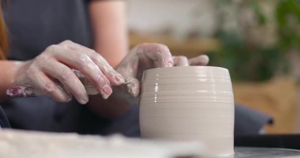手工制陶的概念。女人们手拉手在陶器工作室里的特写。从陶瓷轮上剪下工件.杯子的制作。慢动作. — 图库视频影像