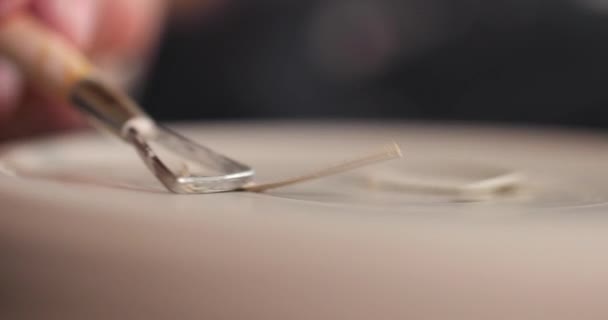 Gros plan des mains de femmes qui façonnent la pièce avec un outil dans un atelier de poterie. Des copeaux d'argile. Mouvement lent — Video