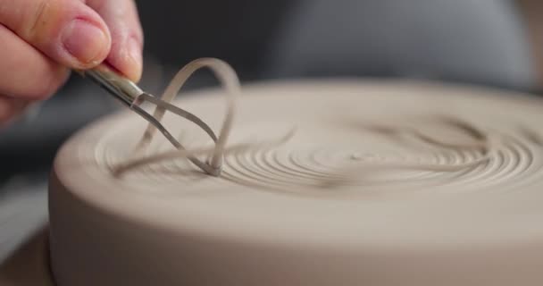 Primo piano di mani di donne che plasmano il pezzo con uno strumento in uno studio di ceramica. trucioli di argilla. Rallentatore — Video Stock
