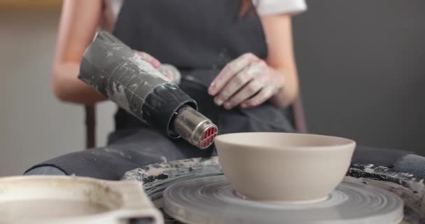 Medelhög bild av unga kaukasiska kvinnliga keramik i keramik verkstad. Kvinna i förkläde torkar keramik tomt på roterande hjul på keramik studio. Långsamma rörelser — Stockvideo