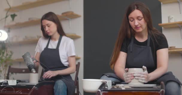 Aardewerk studio concept. Twee jonge vrouwen met aardewerk wiel, handgemaakte keramiek, creatief. Langzame beweging — Stockvideo