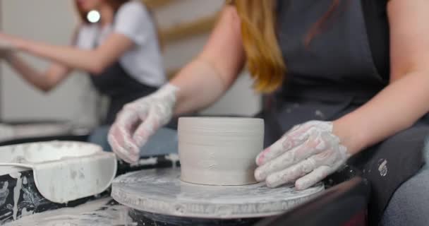 Handen van jonge vrouw in aardewerk studio met behulp van aardewerk wiel, handgemaakte keramiek, creatief. Close-up, slow motion — Stockvideo