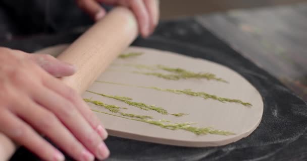 O mestre deixa a impressão das plantas no tabuleiro de barro no estúdio de cerâmica. Crie louças de barro feitas à mão. Close-up, câmera lenta — Vídeo de Stock