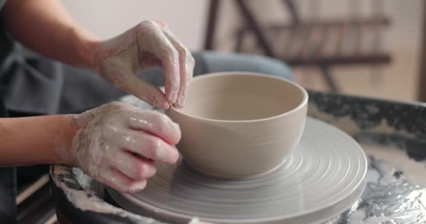 Handmade ceramics concept. Close-up of womans hands in pottery studio. Cuts the workpiece from pottery wheel. Top view. Slow motion — Stock Video