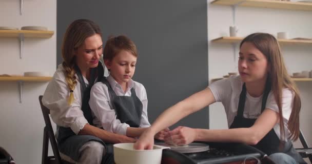 Maestro vasaio insegnamento madre con il suo bambino in laboratorio di ceramica. Giovane donna e bambino che studia ceramica in studio. Rallentatore — Video Stock