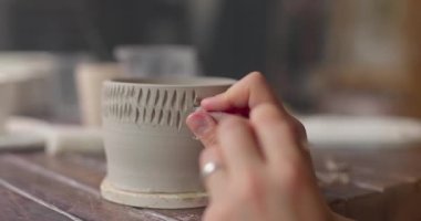 Çömlekçi, kil kaseyi bıçak aletiyle süslüyor. El yapımı seramik konsepti. Potter oymacılığı. Yakın çekim, yavaş çekim.