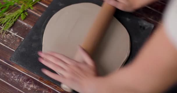 Dłonie kobiety płaski kawałek gliny leżącej na tkaninie za pomocą drewnianego wałka w studiu ceramicznym. Zbliżenie, spowolnienie — Wideo stockowe