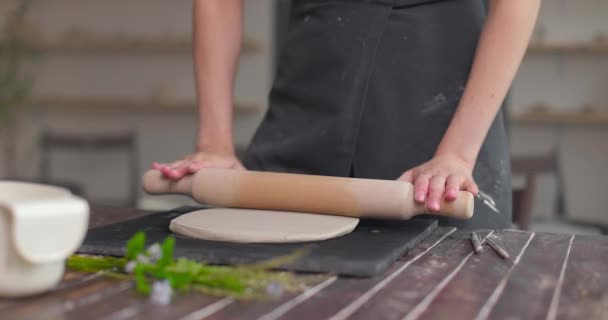 Kvinnlig krukmakare rullar ut platta bit lera ligger på tyg med hjälp av trä rullande stift i keramiska studio. Närbild, slow motion — Stockvideo