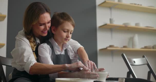 Die junge Mutter und ihr süßer kleiner Sohn arbeiten gemeinsam an der Töpferscheibe. Handgefertigte Keramik-Werkstatt. Zeitlupe — Stockvideo