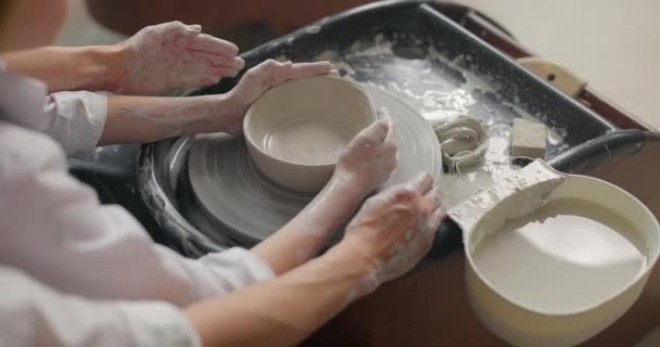 A mãe ensina o filho a trabalhar numa roda giratória de cerâmica. Close-up de mãos. Hobby, lazer, artes e artesanato conceito. Movimento lento — Vídeo de Stock