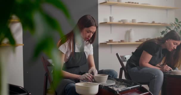 Dos mujeres están trabajando con la rueda de cerámica haciendo ollas durante la clase magistral para adultos, pasatiempo artesano creativo. DIY Actividades de ocio y concepto de artesanía. Movimiento lento — Vídeos de Stock
