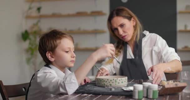 妈妈在画室帮她儿子画碗.陶器班的工作坊妈妈和孩子在一起做创造性的工作。慢动作 — 图库视频影像