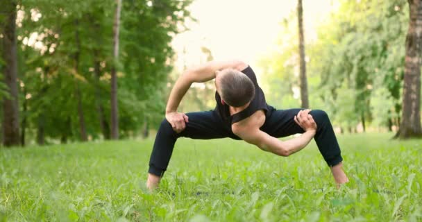 Uomini che praticano yoga e meditano nel parco nella soleggiata giornata estiva. Giovane che fa yoga posa al mattino. Rallentatore — Video Stock