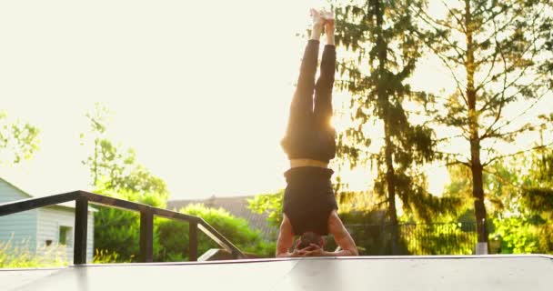 Jovem praticando perna estendida headstand ioga pose fora no parque.Yoga professor alongamento ao ar livre — Vídeo de Stock