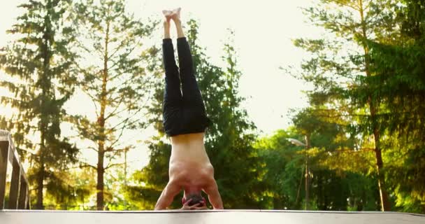 Muskularny mężczyzna robi asana na głowie w przyrodzie.Yogi gołe klatki piersiowej medytacji w słoneczny dzień. — Wideo stockowe