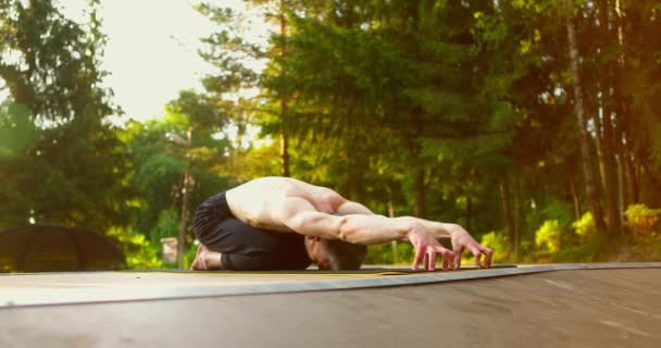 El hombre se calienta durante el entrenamiento matutino. Yogui sentado en las rodillas y estirando las manos en el frente. Dedos en las yemas de los dedos. — Vídeos de Stock