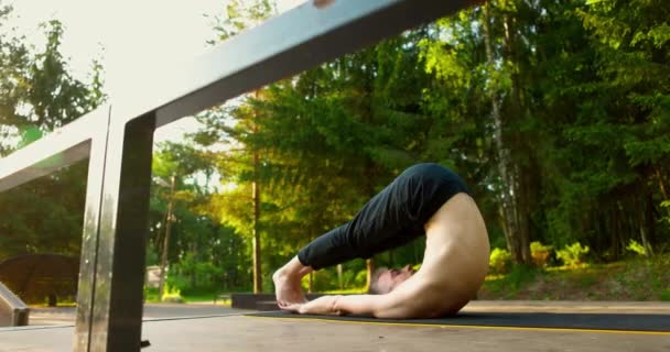 Yogi ligger på rygg med utsträckta händer och benen slängda bakom huvudet — Stockvideo