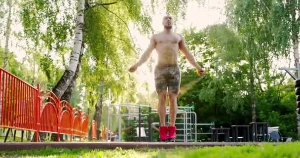 Hombre deportivo saltando con la cuerda que salta en el terreno de los deportes.Atleta practicando saltos básicos con la cuerda que salta — Vídeos de Stock