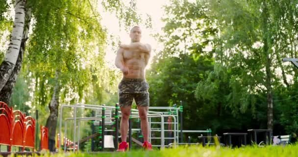 Handsome young sportsman performing warming up exercises during workout at sports ground — Video