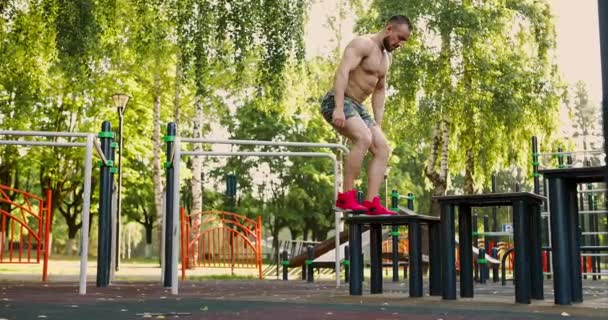 若い筋肉のスポーツマンは午前中の屋外ワークアウト中にジャンプ演習を行う — ストック動画