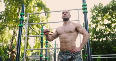 Trisepsler için egzersiz yapan atletik bir adam. Sıcak bir sabahta dışarıda direnç bandıyla.