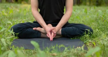Nilüfer pozisyonundaki adam şehir parkında meditasyon yapıyor. Dibe yakın çekim yavaş çekim..