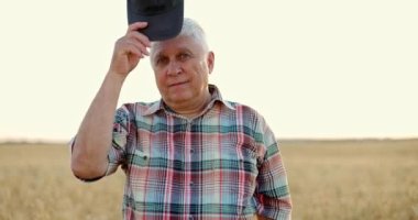 Yazın sonunda hasat mevsiminde buğday tarlasında duran kıdemli çiftçi.