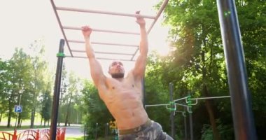 Spor sahasındaki maymun parmaklıklarını kullanan beyaz bir genç. Maymun parmaklıkları üzerinde egzersiz yapan kaslı bir adam. Yavaş çekim