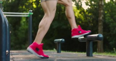 Spor salonunda spor ayakkabısı giymiş kaslı bir adam. Yazın spor salonunda. Barda atlayan bir adam.
