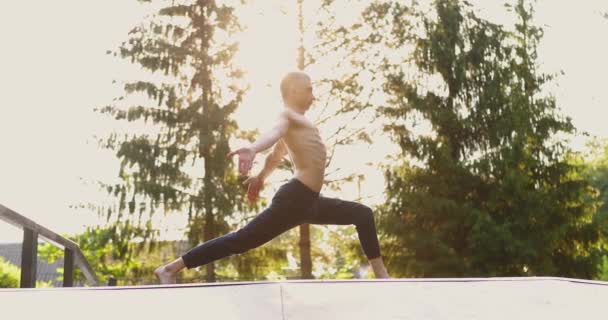 Homem atlético fazendo ioga pose e pilates exercícios no parque verde agradável. Masculino fazendo ioga ao ar livre. Conceito esporte, saúde, fitness, bem-estar, estilo de vida ativo. Movimento lento — Vídeo de Stock