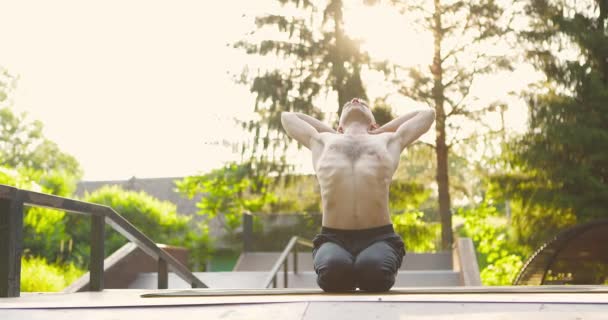 Hombre haciendo ejercicios de yoga en la plataforma de madera al aire libre.Yogui en ropa deportiva que se extiende hacia atrás, avanzando — Vídeos de Stock